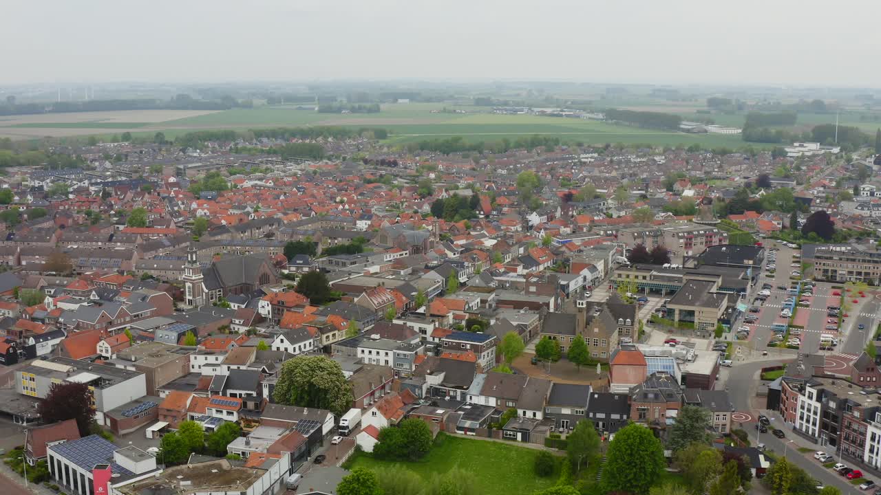 Synkende luftfoto av Axel sentrum i Nederland, tatt på en skyet dag med tåkete bakgrunn.