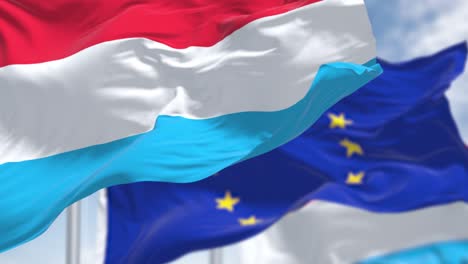 detalle de la bandera nacional de luxemburgo ondeando en el viento con la bandera borrosa de la unión europea en el fondo