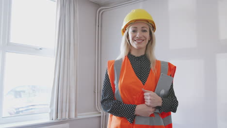 retrato de una topógrafa con sombrero rígido y chaqueta de alta visibilidad con tableta digital realizando una inspección de la casa