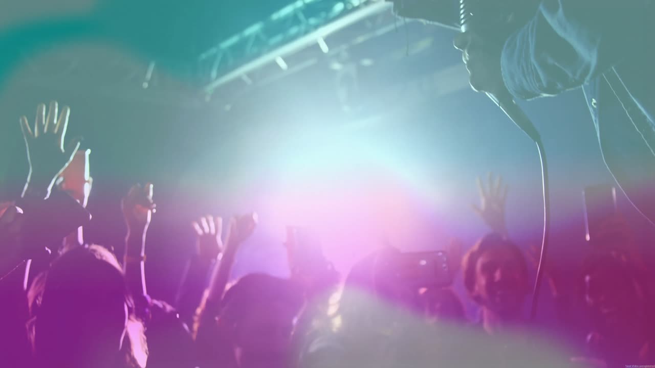 Musicista che si china sulla barriera e interagisce con la folla del concerto mentre le luci si accendono e i fan alzano i telefoni.
