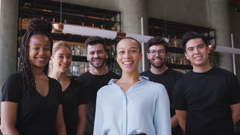 Porträt-Einer-Lächelnden-Besitzerin-Einer-Restaurantbar-Mit-Einem-Team-Von-Kellnern,-Die-An-Der-Theke-Stehen