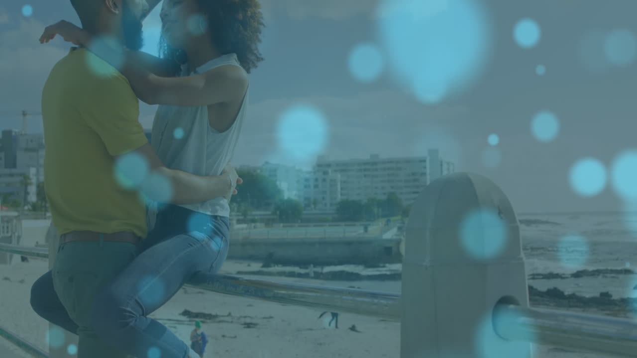 animación de puntos de luz sobre una pareja afroamericana abrazándose en la playa