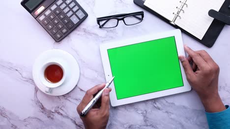 persona usando una tableta con una pantalla verde en un escritorio de mármol