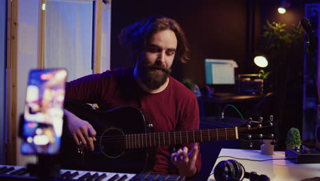 artist recording himself at home singing and playing acoustic guitar