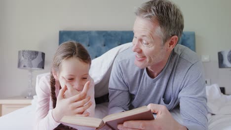 Father-and-daughter-interacting-with-each-other-while-reading-a-book-4k