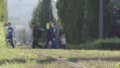 grass grow between tram rail tracks near oslo central station, citizens crossing