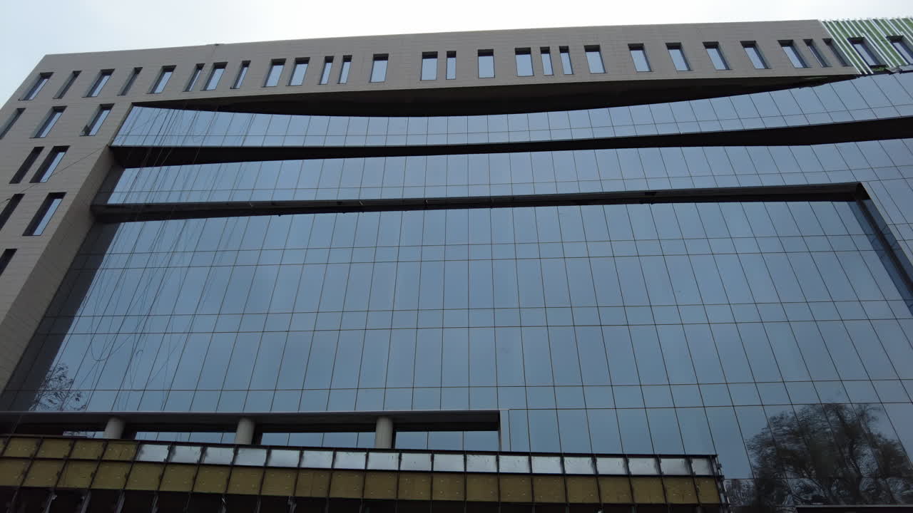 A striking view of a contemporary building featuring a sleek glass exterior. This structure reflects its surroundings, showcasing a blend of design and functionality in an urban environment