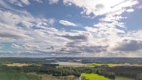 aerial hyperlapse of cloudscape drifting over lush swedish countryside, tilt-up