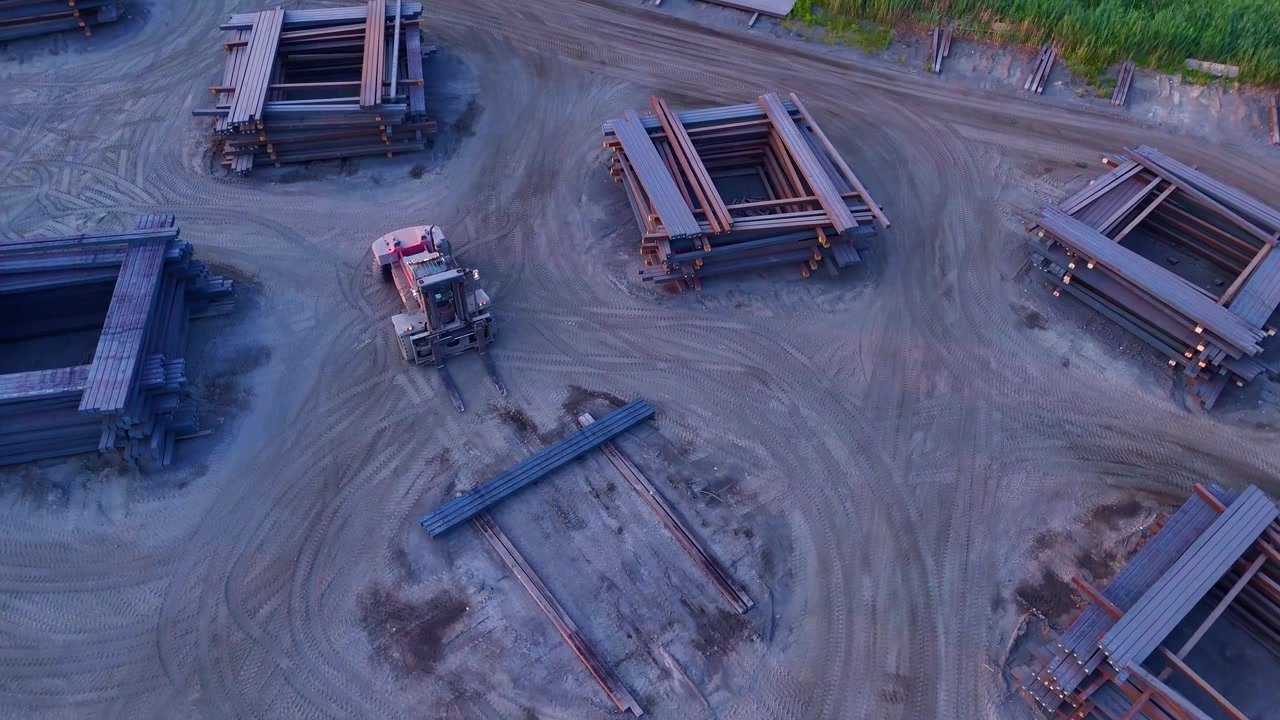 Aerial view of a forklift moving recycled steel beams in a mill yard in Monroe, USA