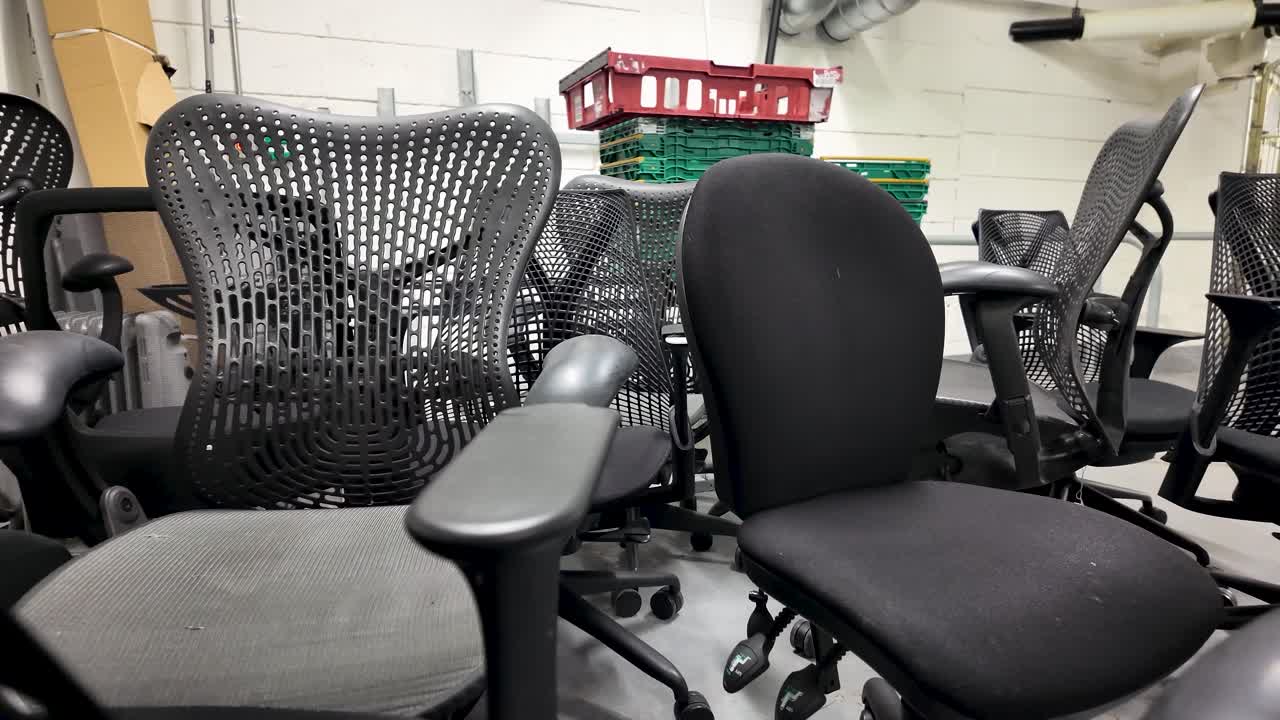 Various office chairs placed in storage within a basement or utility room