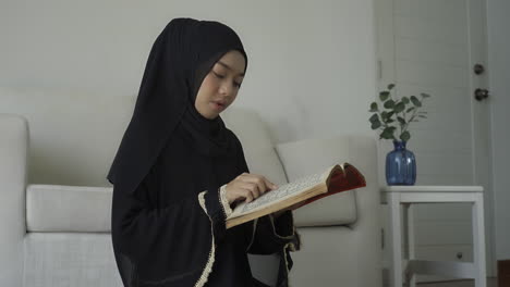 an asian muslim woman reciting salah or salat al-fatiha passage of the qur'an, in a single act of sujud called a sajdah or prostrations at home