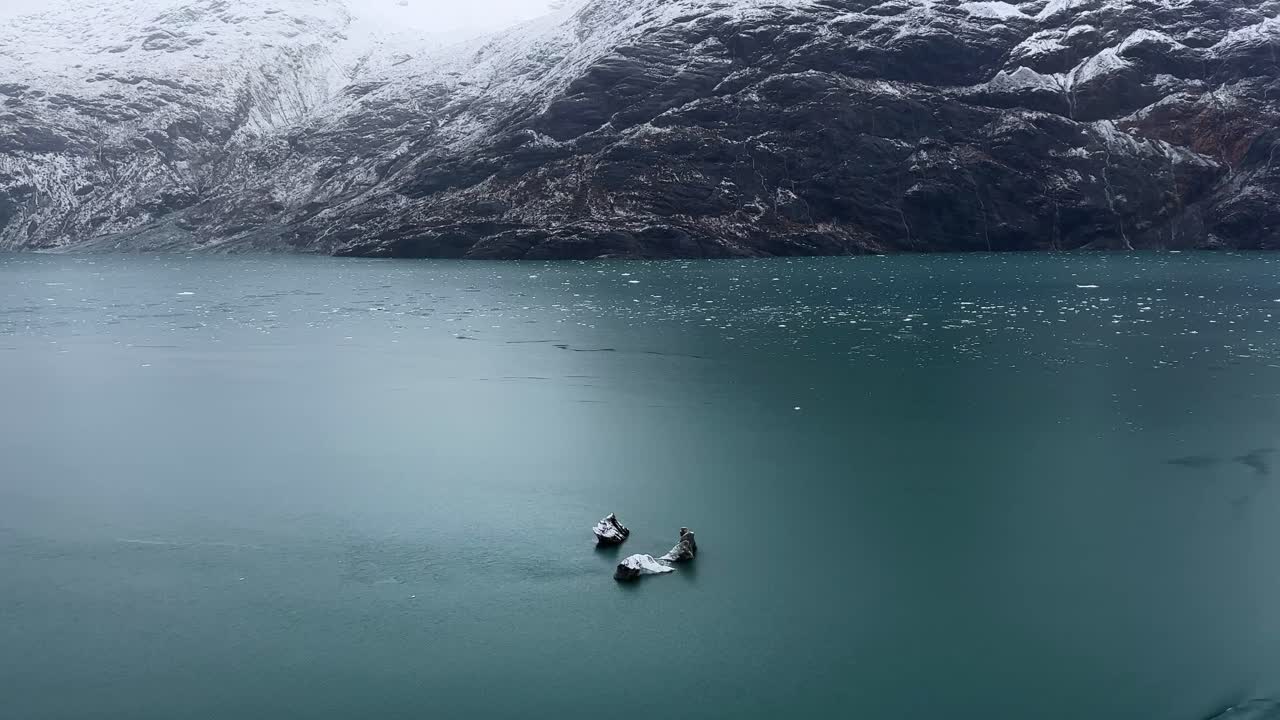 Håndholdt opptak fra et skip i bevegelse som passerer et flytende isfjell i kjølige Glacier Bay, Alaska. 4K