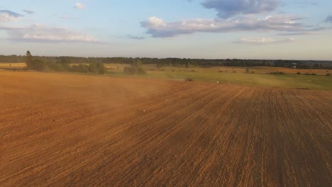 heavy agricultural machinery with implements in agricultural fields on a sunny summer evening