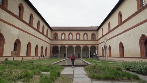 Mujer-Por-Detrás-Caminando-En-El-Patio-Del-Castillo-Sforza-A-La-Piscina-De-Agua