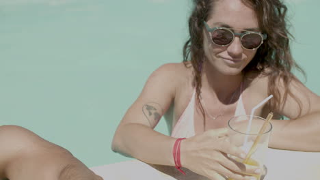 close up of man and woman drinking beverages and clinking glasses in swimming pool