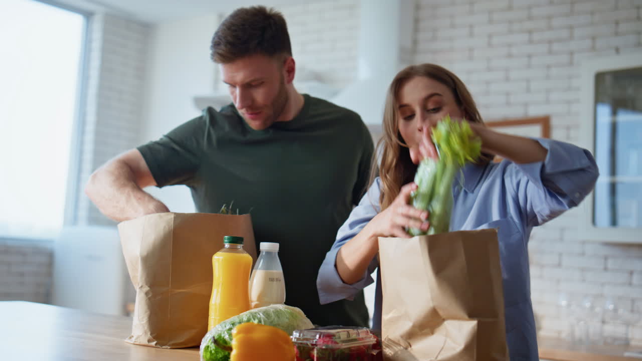 Couple unpacking delivered products talking at cozy kitchen together closeup