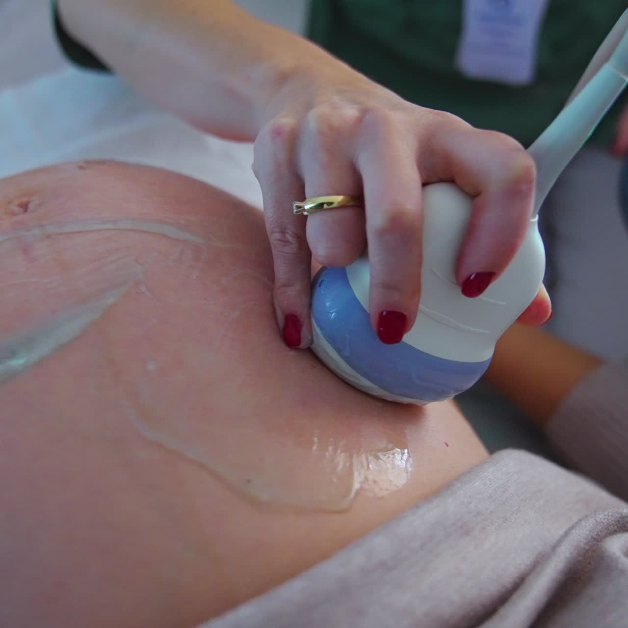 Hand of a doctor holding ultrasonic device moves by the big pregnant belly of a patient. Close up. Ultrasound check up concept