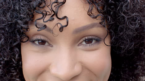 close-up of woman with curly hair smiling and looking at camera
