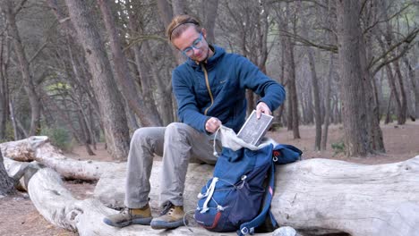 slow motion shot of a man sitting on a fallen tree packing away his book