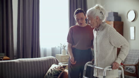 young woman assisting elderly grandmother with walker at home