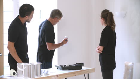 Decorador-Instruyendo-A-Jóvenes-Colegas-A-Pintar-Una-Habitación