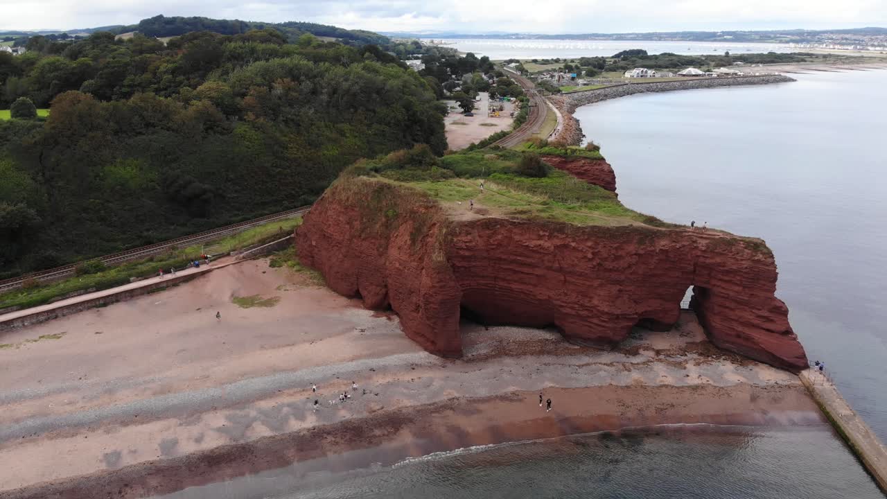 Aerial view of the stunning red sandstone cliffs on the Dawlish coastline in Devon, England, showcasing the unique rock formations and coastal scenery. parallax shot