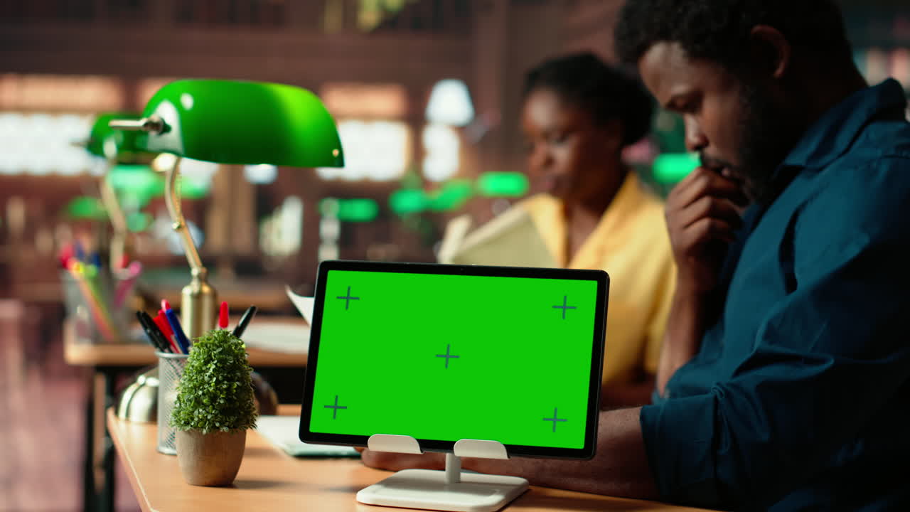 estudiantes afroamericanos consultando trabajos de investigación junto a la pantalla verde