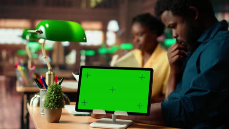 african american students consulting research papers next to green screen
