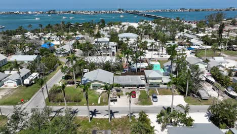 luxury residential area of american town in florida with palm trees and blue river water in background. aerial wide shot. cruising boats on clear bay with bridge in distance.