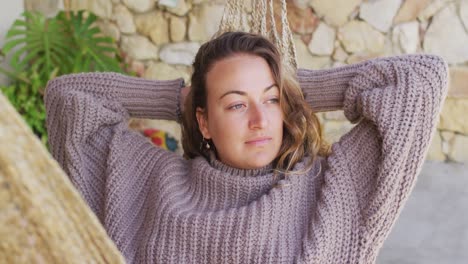 Smiling-caucasian-woman-lying-in-hammock-relaxing-and-enjoying-the-view-from-sunny-garden-patio