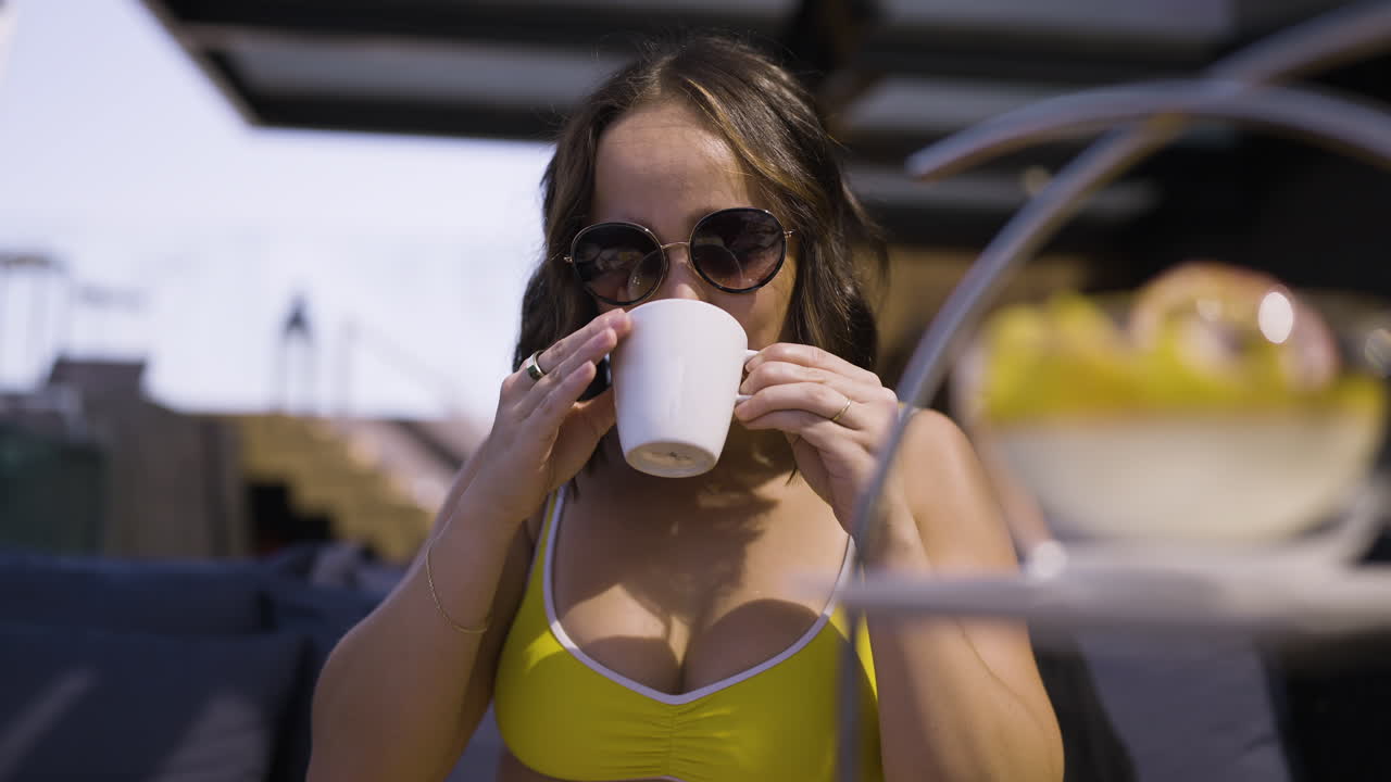 toma en cámara lenta de una mujer feliz y atractiva en bikini tomando una bebida caliente