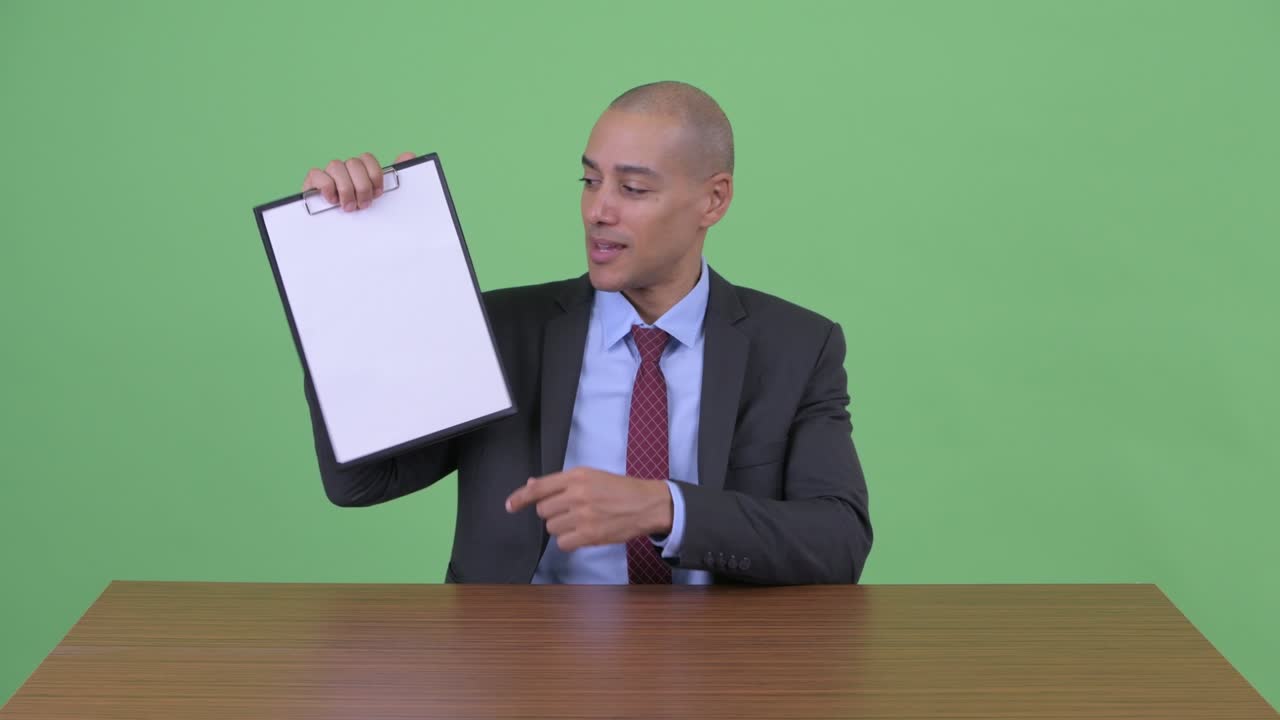Happy handsome bald multi ethnic businessman at office desk