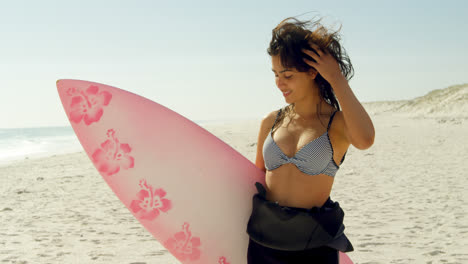 Female-surfer-playing-with-her-hair-on-the-beach-4K-4k