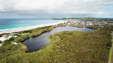 Drohne-Steigt-Auf-Und-Enthüllt-Den-Teebaumsee-An-Der-Küste-Mit-Strand-Im-Hintergrund