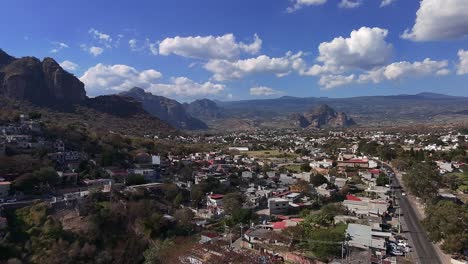 backward aerial view of oaxtepec and tlayacapan, morelos, surrounded by rocky mountains under a cloudy blue sky