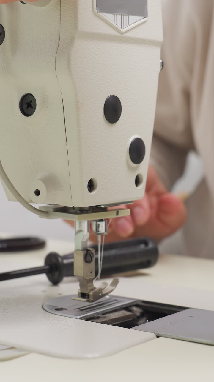 Quality check test stitch on machine with closeup needle plate and hands adjusting feed detailed inspection of stitch formation, screwdriver nearby, controlled studio lighting and professional