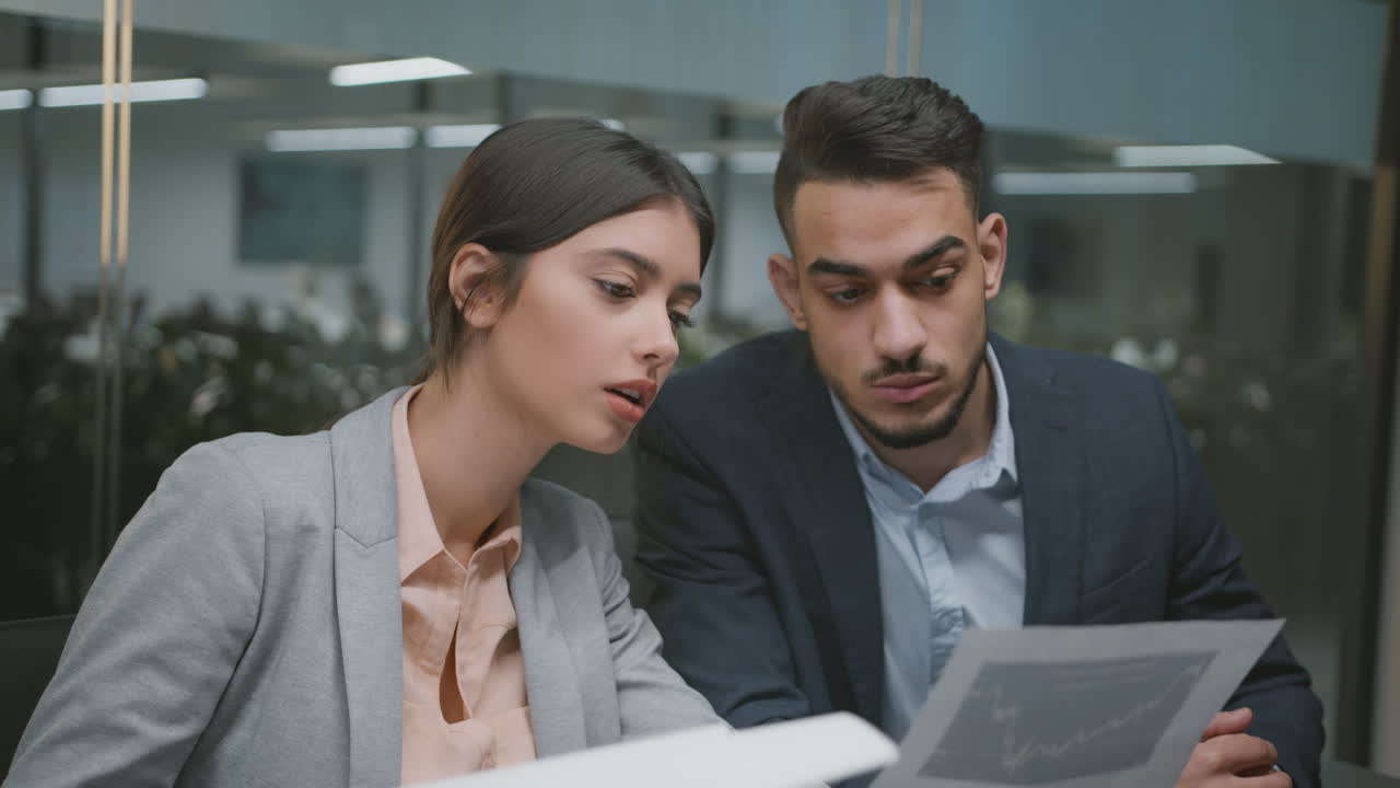 Two business professionals discussing documents in an office setting