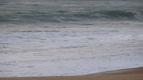 Mittlere-Wellen-Krachen-Am-Strand-Vorbei,-Mit-Wunderschönem-Goldenen-Sonnenuntergangslicht