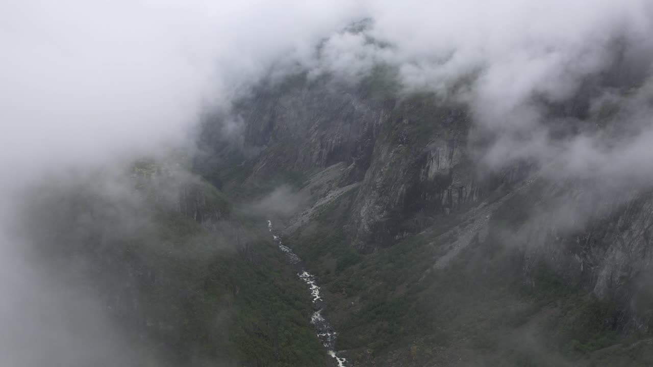 drone dolley disparado entre la población de velo delgado sobre el estrecho río bjoreio con agua de deshielo que serpentea desde el voringsfossen entre las empinadas paredes montañosas de hardangervidda en noruega