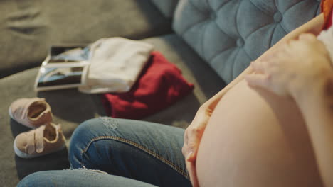 pregnant woman with baby items and ultrasound pictures
