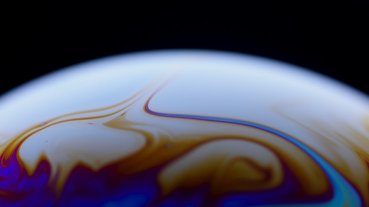 Colorful close up surface of a soap bubble with abstract psychedelic background and patterns on black background. Vivid rainbow colors in weird and strange patterns. Close up. Slow motion