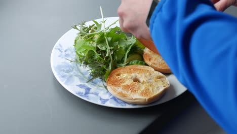 woman making an egg bagel and salad for breakfast