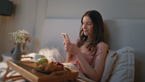 relaxed girl typing message in home bed closeup. attractive dreamy woman lying