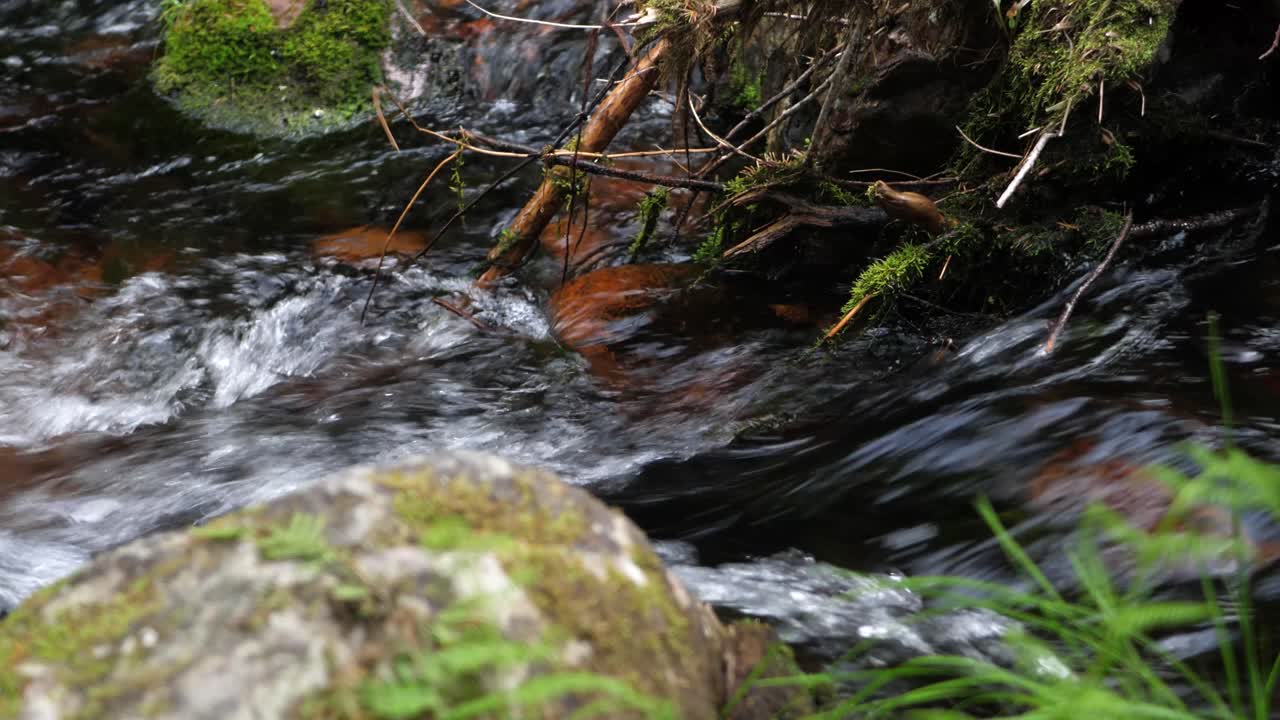 Static Extreme close up of rocky fresh water stream from Njupeskär waterfall, green moss filled stones, at Fulufjället National Park in Särna, Sweden