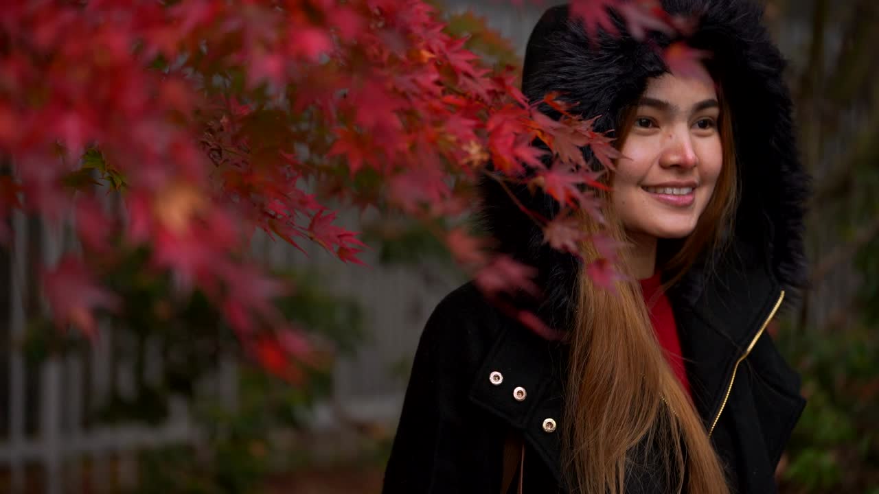 4K Beautiful woman standing and smiling under the Red maple tree in garden.
