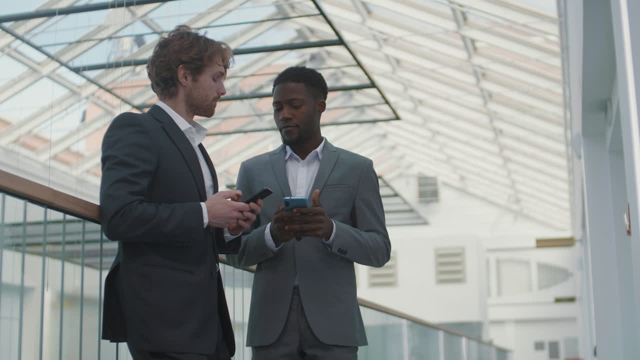 dos hombres de negocios hablando y usando teléfonos celulares