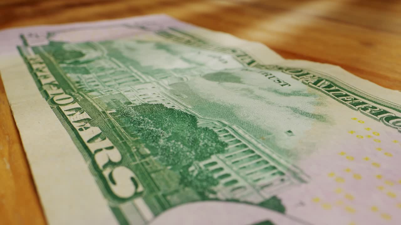 A closeup view of a fifty dollar bill on a polished wooden table, highlighting its intricate design