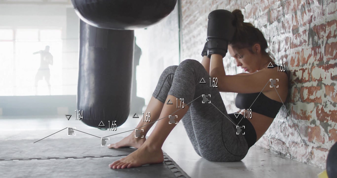 Young woman in boxing gloves resting against gym wall with data overlay animation