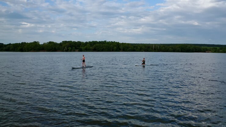 Couple on stand up paddle board. Aerial view of people standing on sup board and swims surfing