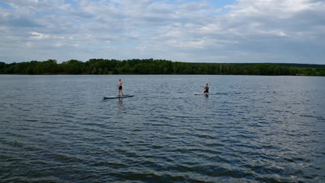 Couple on stand up paddle board. Aerial view of people standing on sup board and swims surfing